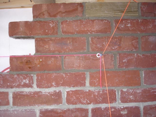 Mason building a brick wall using color-coded story poles